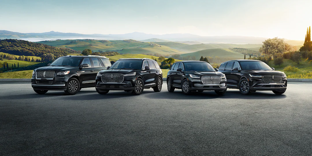 Lineup of Lincoln vehicles on road in front of hills