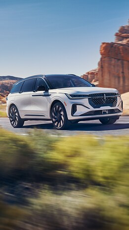 Lincoln Nautilus™ SUV driving on road next to rock structure