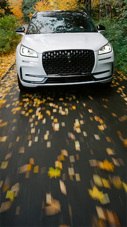 White Lincoln Corsair® Reserve SUV on a road with fallen leaves