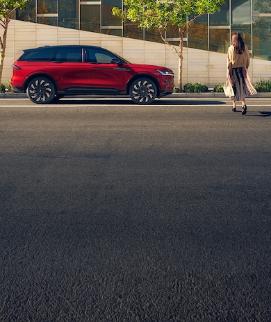 A woman crosses a city street and approaches a parked 2026 Lincoln Nautilus® SUV