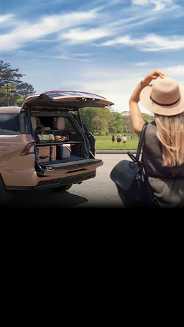 Person looking at kids running in the distance with Lincoln® Navigator trunk open next to her