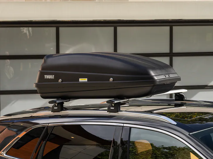 A Lincoln SUV parked in driveway with mounted cargo box on roof
