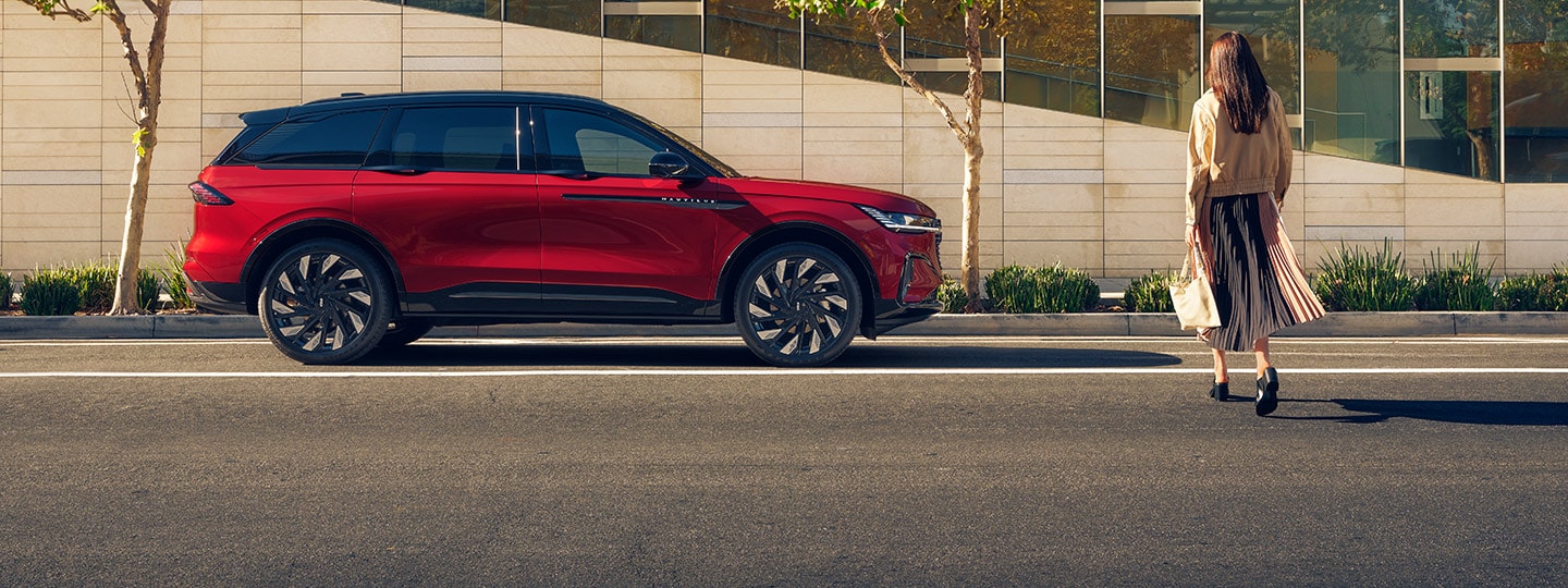 A woman crosses a city street and approaches a parked 2026 Lincoln Nautilus® SUV