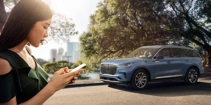 Person looking at phone with Lincoln® Aviator in the background
