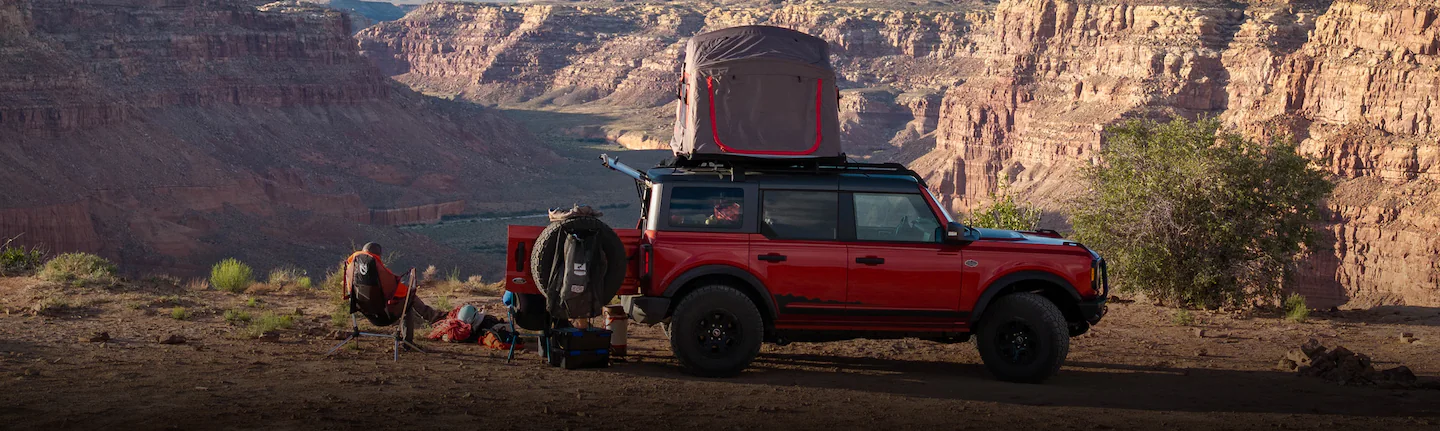 A 2025 Ford Bronco® in a canyon with people camping and a rooftop tent