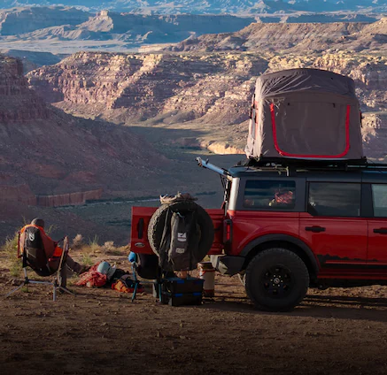 A 2025 Ford Bronco® in a canyon with people camping and a rooftop tent