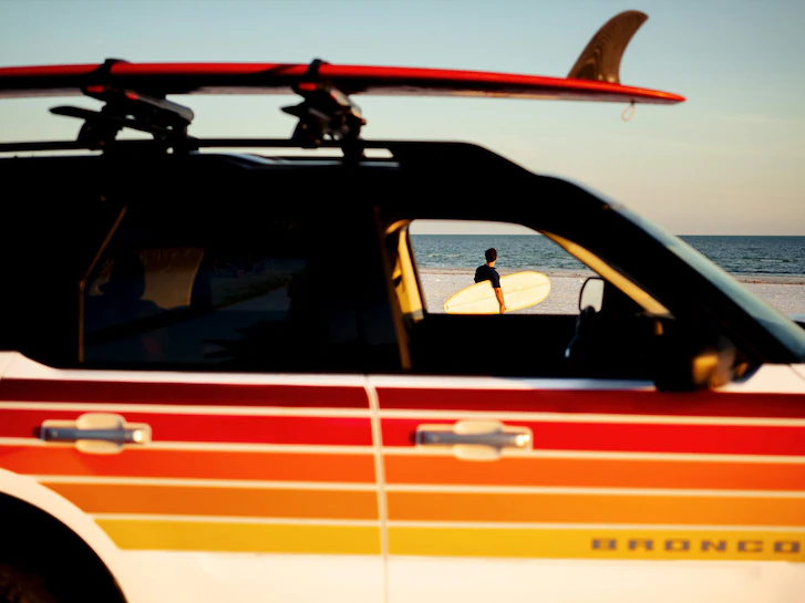 Close-up of a 2024 Bronco Sport® SUV with surfboard on mounted roof crossbars