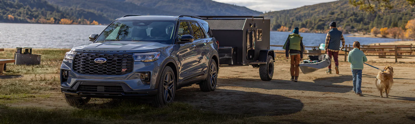 A 2025 Ford Explorer® SUV parked near a lake towing a trailer and near people going kayaking