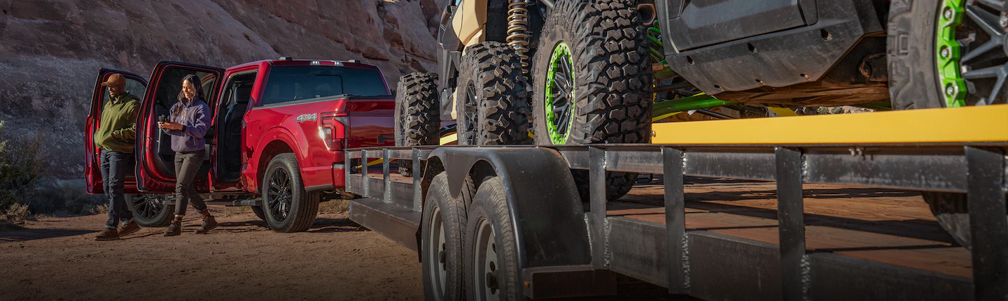 A 2025 Ford Truck F-150® parked with a trailer loaded with UTVs