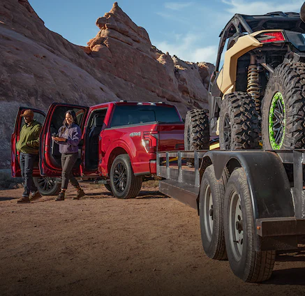 A 2025 Ford Truck F-150® parked with a trailer loaded with UTVs