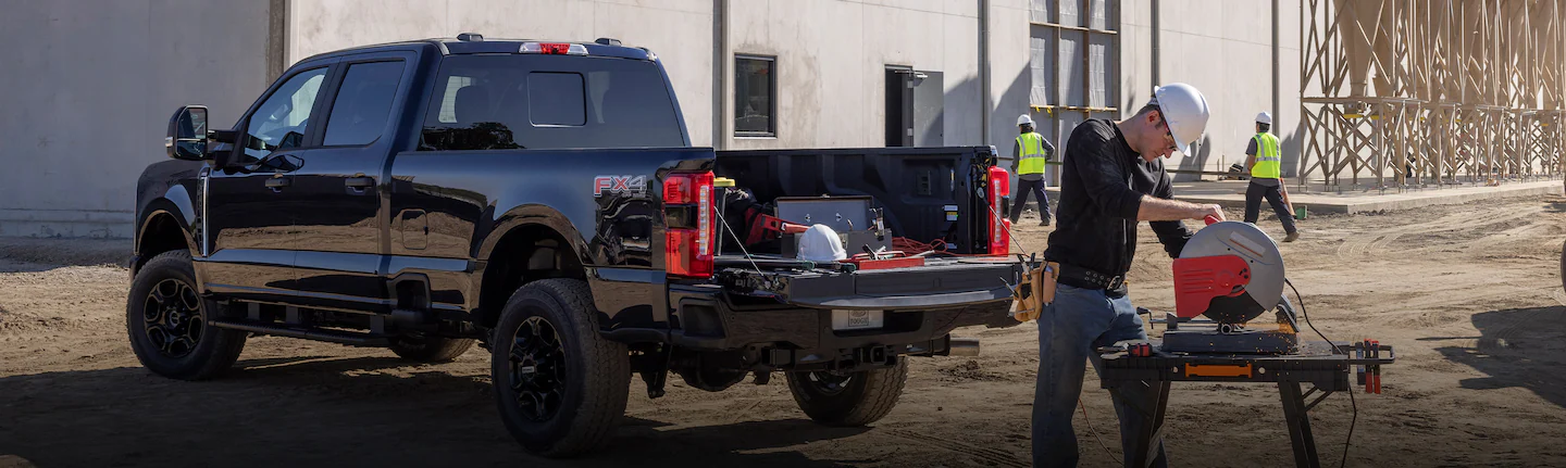 A Ford Super Duty®250® truck parked with tools in truck bed as construction workers work