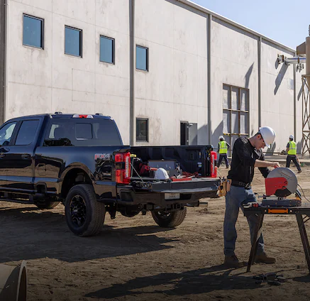 A Ford Super Duty®250® truck parked with tools in truck bed as construction workers work