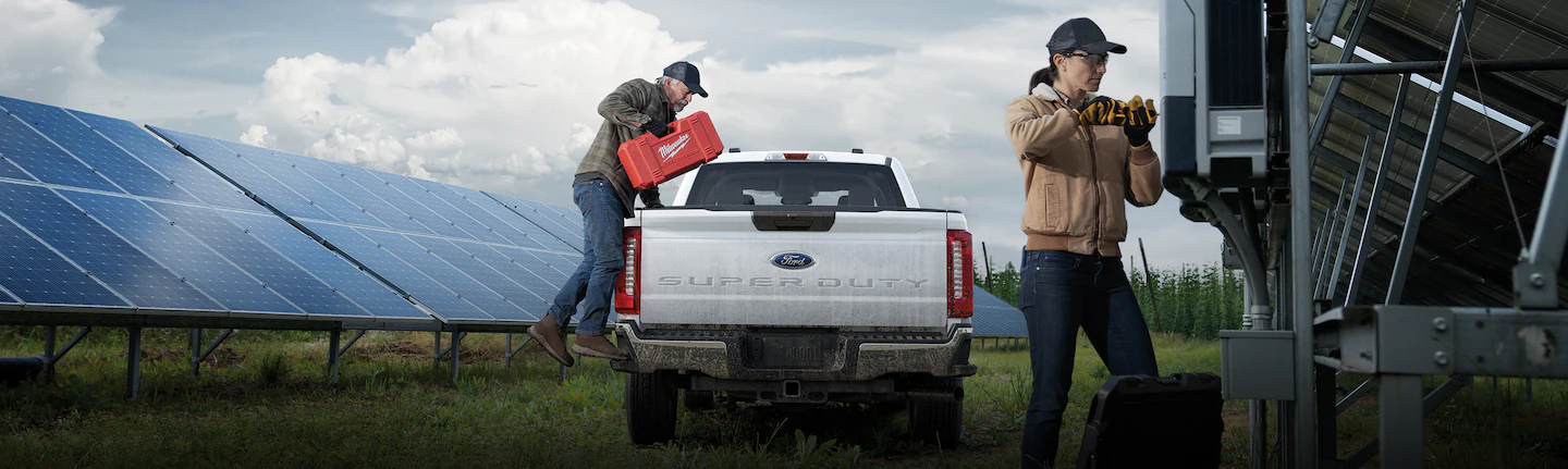 Man loading tools into Ford Super Duty®350® truck while woman works on a solar panel