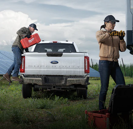 Man loading tools into Ford Super Duty®350® truck while woman works on a solar panel