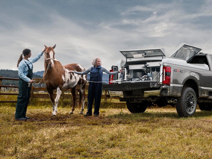 Closeup of a Ford F-250 Super Duty® as a woman looks at a horse with equipment from the bed