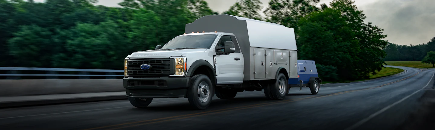 A Ford Super Duty®550® truck pulling a trailer down a paved road