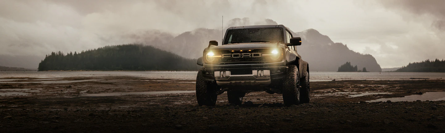 A 2025 Ford Bronco® Raptor® parked on a muddy lake shore at dusk