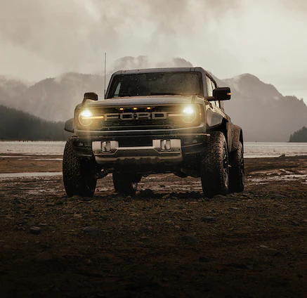 A 2025 Ford Bronco® Raptor® parked on a muddy lake shore at dusk