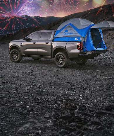A 2026 Ford Ranger® truck parked under a starry, nighttime sky and fireworks with a tent in the truck bed