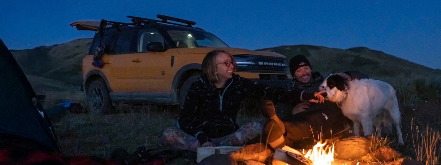 Camping under stars with campfire, dog, and Ford Bronco Sport® SUV