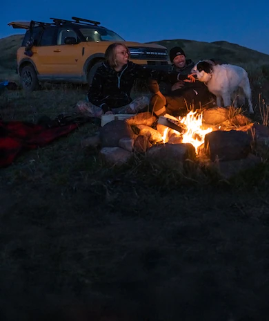 Camping under stars with campfire, dog, and Ford Bronco Sport® SUV