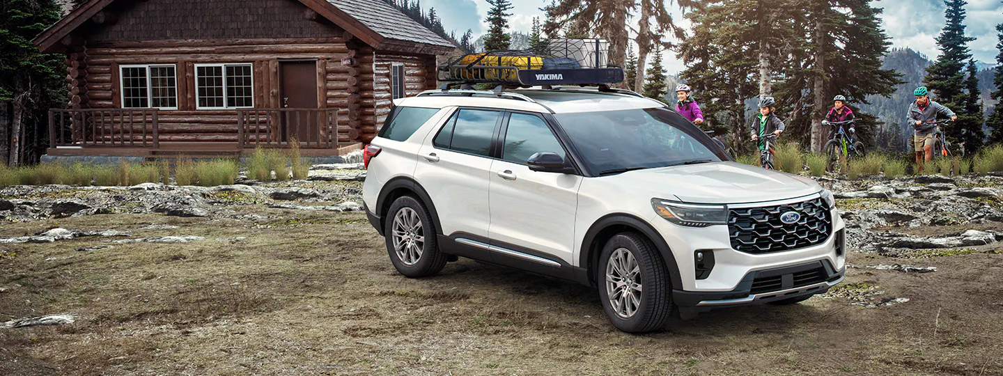 A 2025 Ford Explorer® SUV parked near a camper with people biking