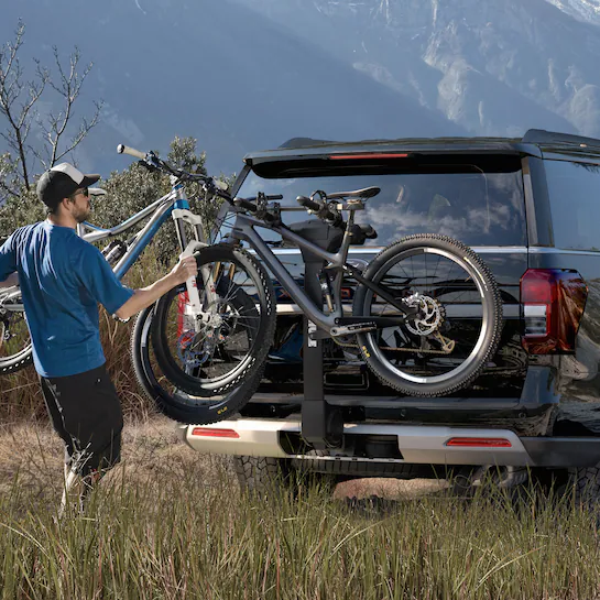 A young man loading a mountain bike onto the back of a 2025 Ford Explorer®