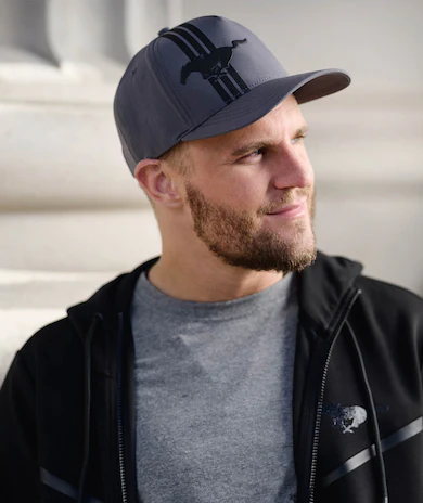 Person in a cap and jacket standing near a stone building