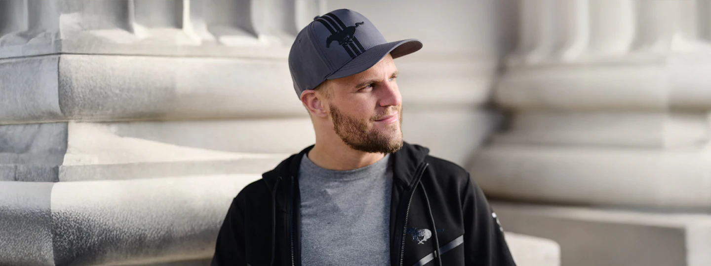 Person in a cap and jacket standing near a stone building