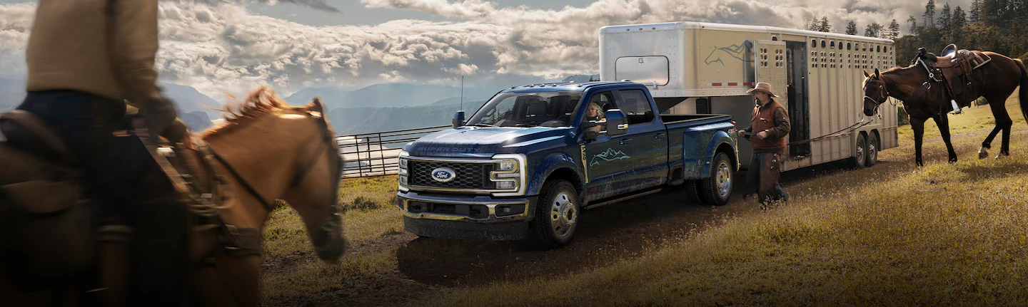 A Ford Super Duty® 450 hailing a large horse trailer as cowboys load horses
