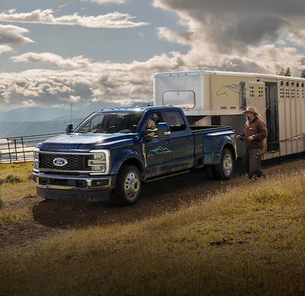 A Ford Super Duty® 450 hailing a large horse trailer as cowboys load horses