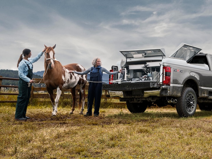 Closeup of a Ford F-250 Super Duty® as a woman looks at a horse with equipment from the bed